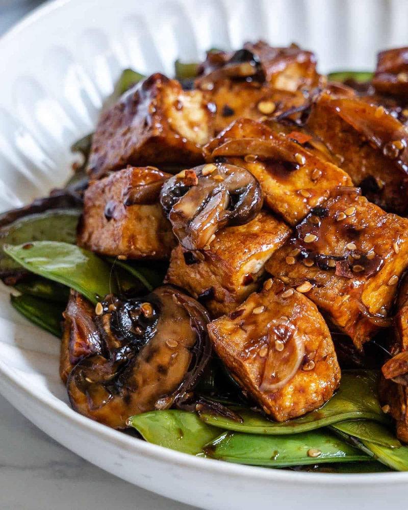 Lightly pan-fried crispy tofu bites tossed with crunchy snow peas, tender mushrooms, and nutty sesame seeds - all coated in a sweet soy glaze with a punch of heat!